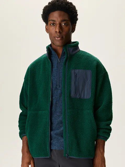 A green fleece jacket with a blue pocket